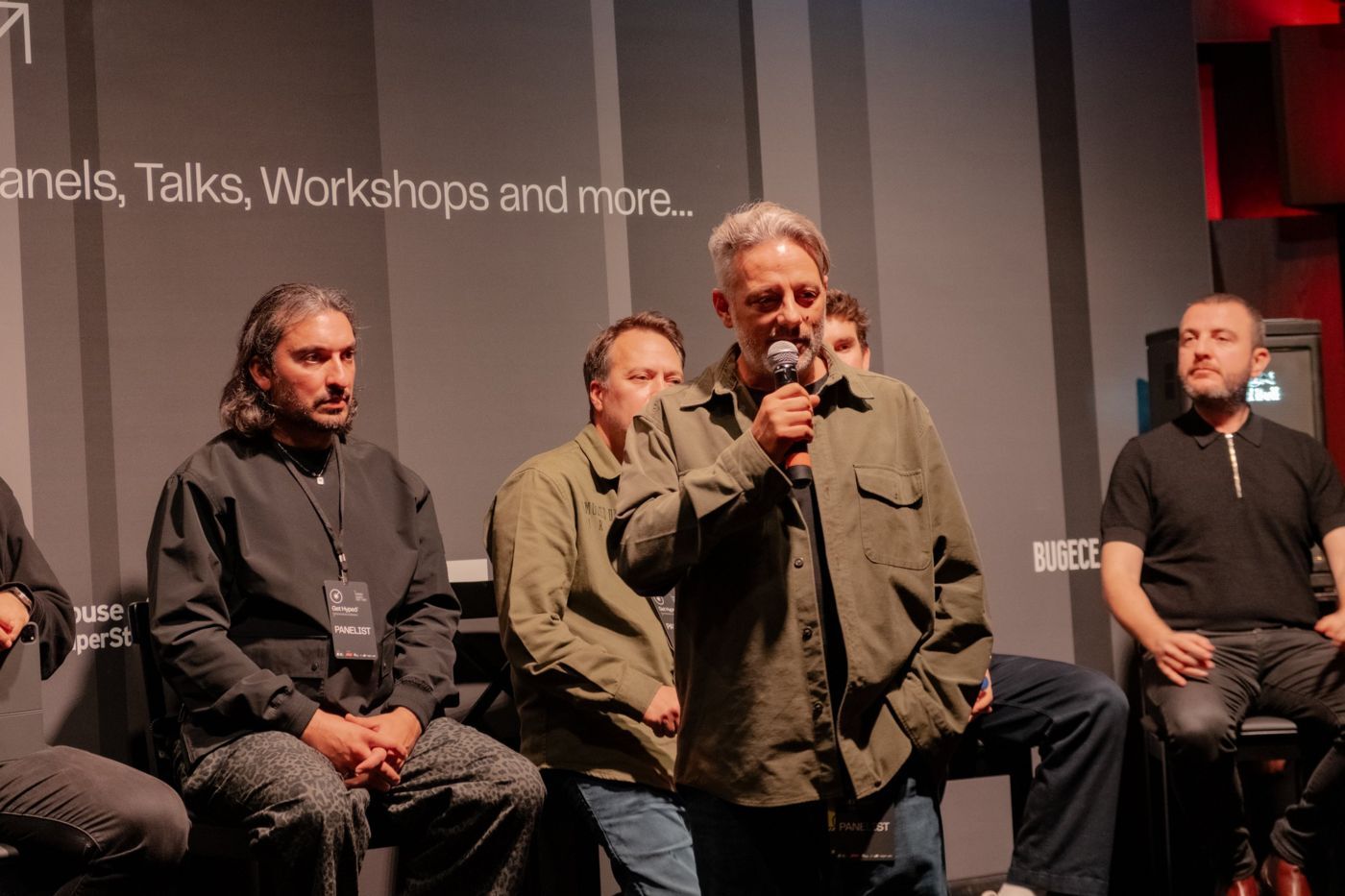 Panelists on stage, one speaking into a microphone