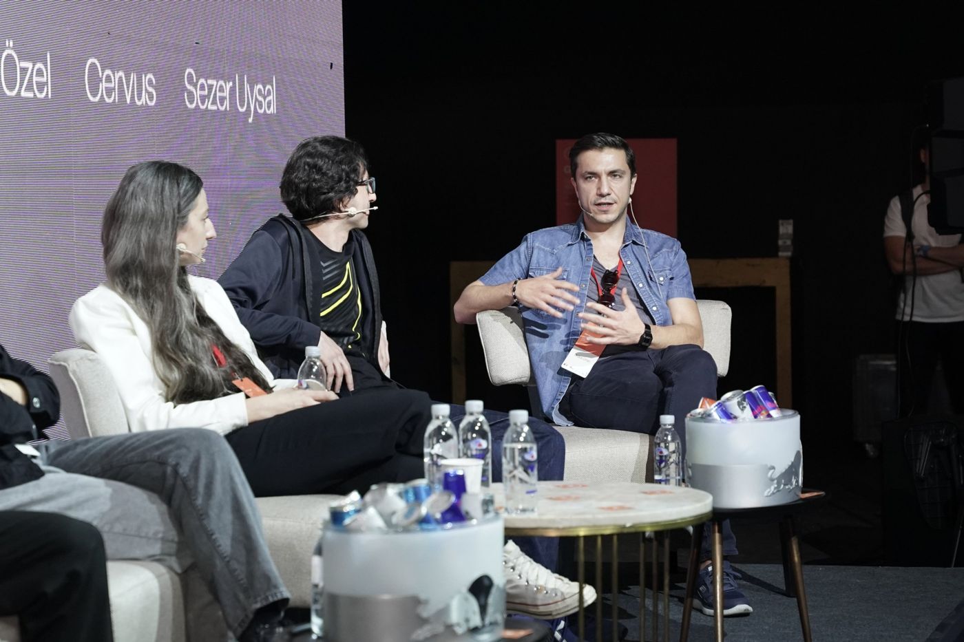 Three panelists in conversation on white sofas